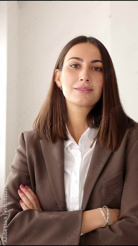 Smiling business woman looking at camera standing in office. Confident portrait of young businesswoman crossing arms. Teamwork concept Smiling business woman looking at camera standing in office. Confident portrait of young businesswoman crossing arms. Teamwork concept