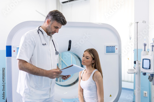 Male doctor explaining MRI scan procedure to female patient inside a diagnostic facility. Hospital Radiographer With Female Patient Operating CT Scanner.