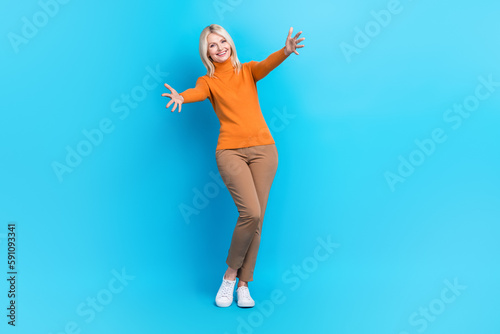 Fototapeta Naklejka Na Ścianę i Meble -  Full length photo of satisfied funny woman wear orange sweatshirt catching present stretch arms to you isolated on blue color background