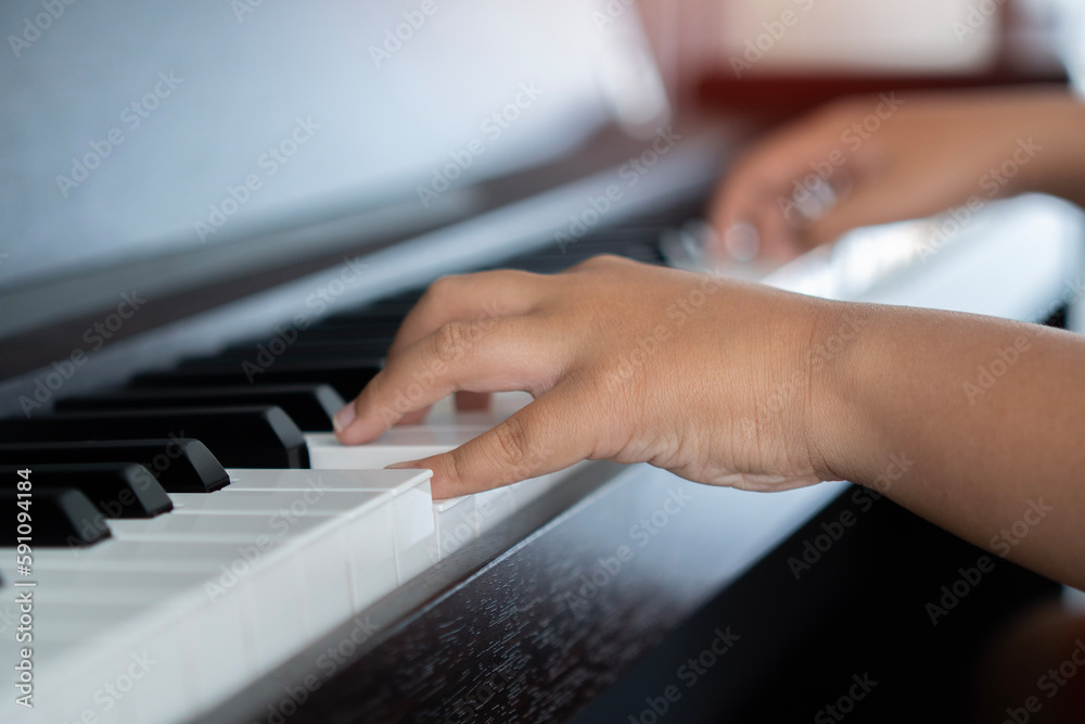 Obraz premium Selective focus to kid fingers and piano key to play the piano. There are musical instrument for concert or learning music.