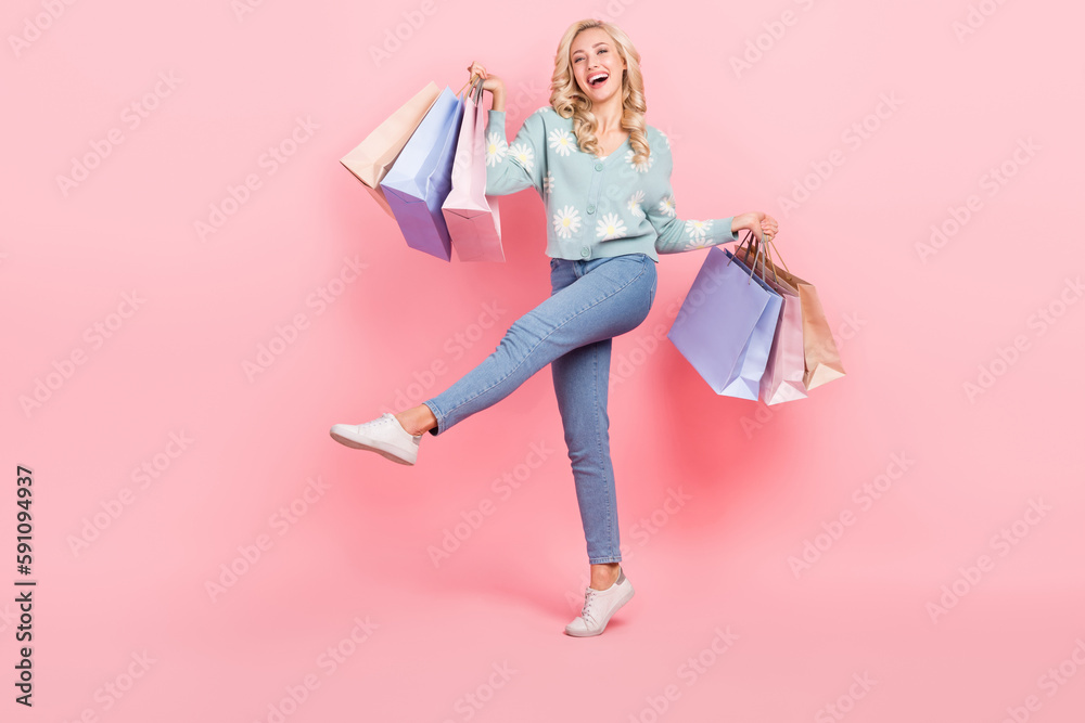 Full length photo of pretty cheerful girl wear flower print cardigan rising shoppers empty space isolated pink color background Full length photo of pretty cheerful girl wear flower print cardigan rising shoppers empty space isolated pink color background