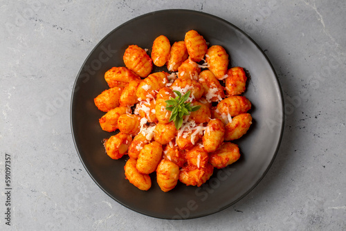 Traditional Italian food potato gnocchi with tomato sauce, parmesan cheese and fresh basil on dark table. Top view. Healthy food.