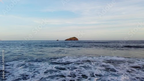 Aerial drone flying low above waves waves with offshore islet of Vacca, Sardinia photo