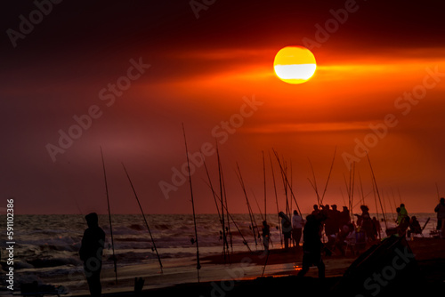 Fishermen with their fishing rods ready to fish on a sunset at the seashore