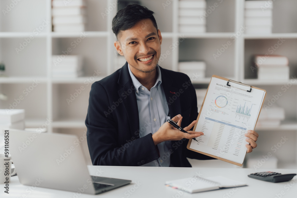 Happy working asian businessman talking on the phone with accounting documents at desk in happy working office Happy working asian businessman talking on the phone with accounting documents at desk in happy working office