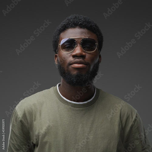 Shot of black guy dressed in casual attire and sunglasses looking at camera.