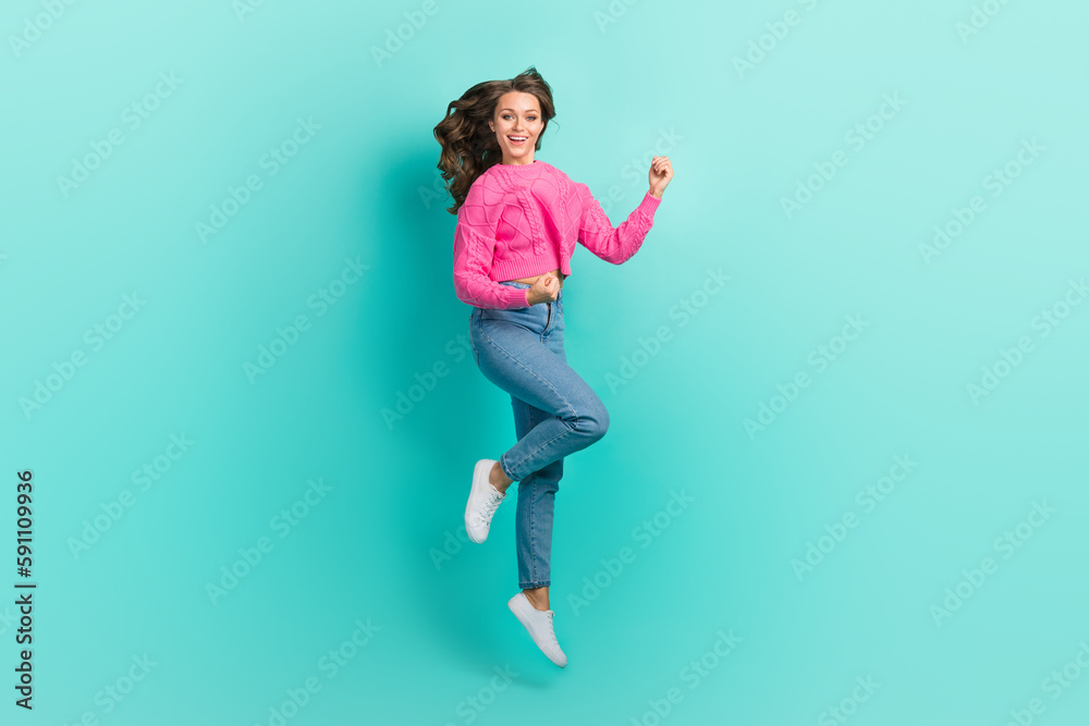Full length photo of cheerful lucky girl wear pink sweater jumping high rising fists isolated turquoise color background