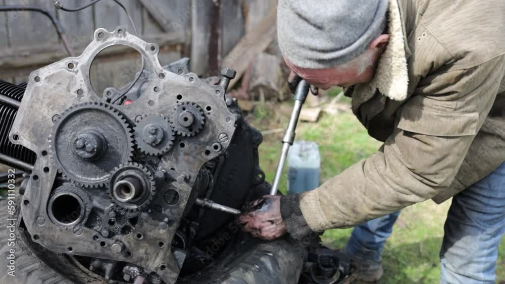 do-it-yourself tractor car engine repair by an old master man on a farm. do-it-yourself tractor car engine repair by an old master man on a farm.