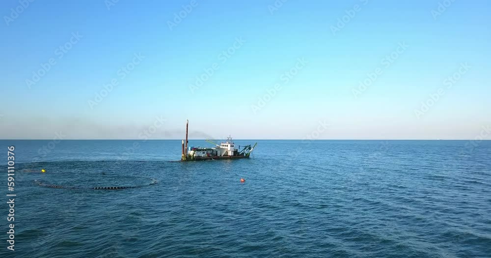 Ship on the sea is grating the sand with the pipes under water Ship on the sea is grating the sand with the pipes under water