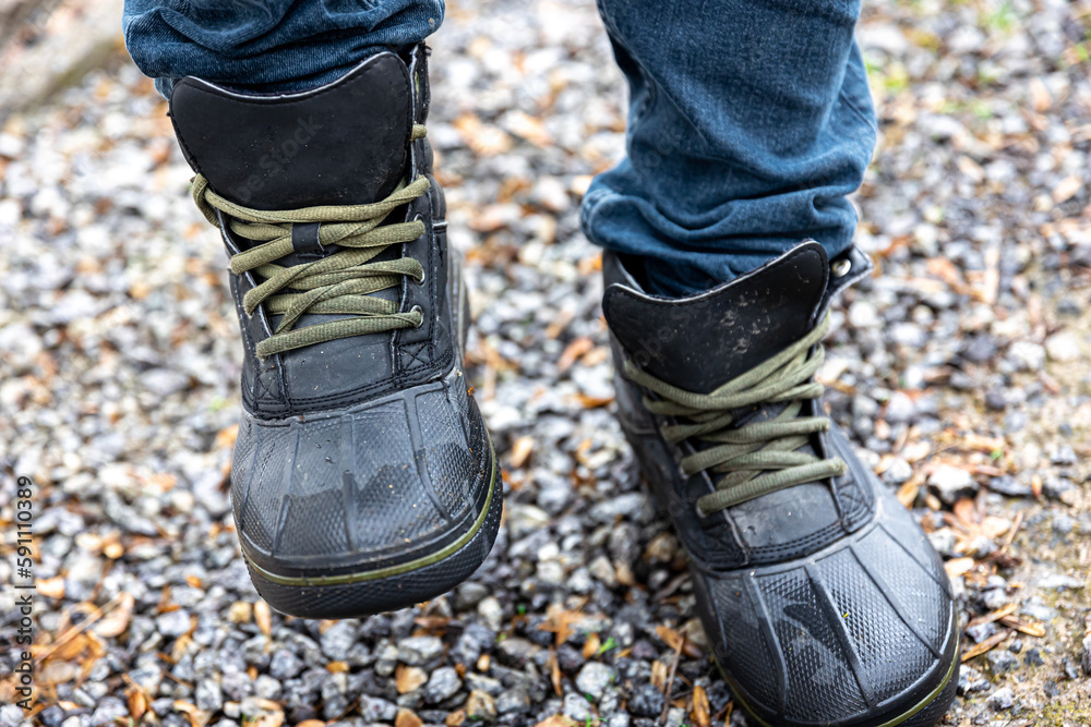 A man in boots stands on gravel, close up.