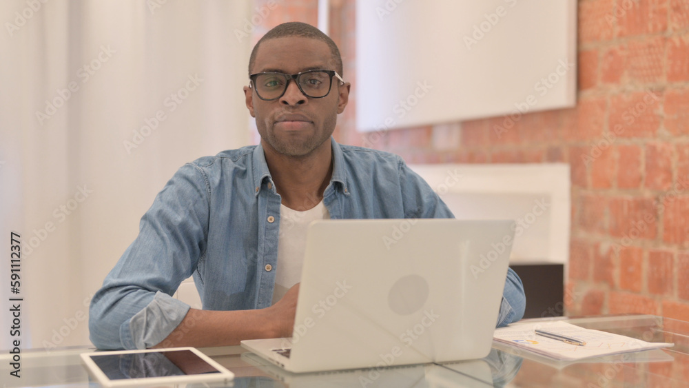 African Man Working on Laptop Looking toward Camera African Man Working on Laptop Looking toward Camera