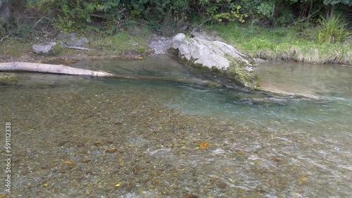 Nice contrast between shallow water flowing over small stones and deeper water running past large rock - Selwyn River at Whitecliffs Domain (New Zealand) photo