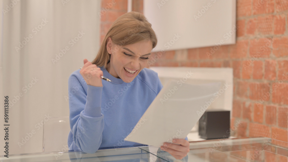 Young Woman Celebrating while Reading Contract