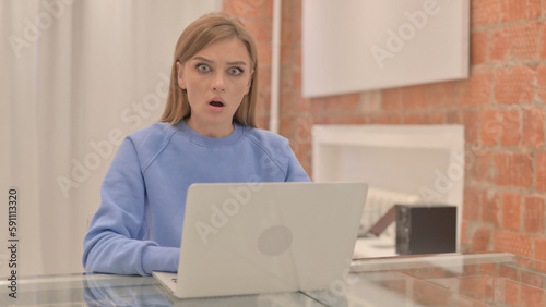 Shocked Young Woman Looking at Camera while Working on Laptop