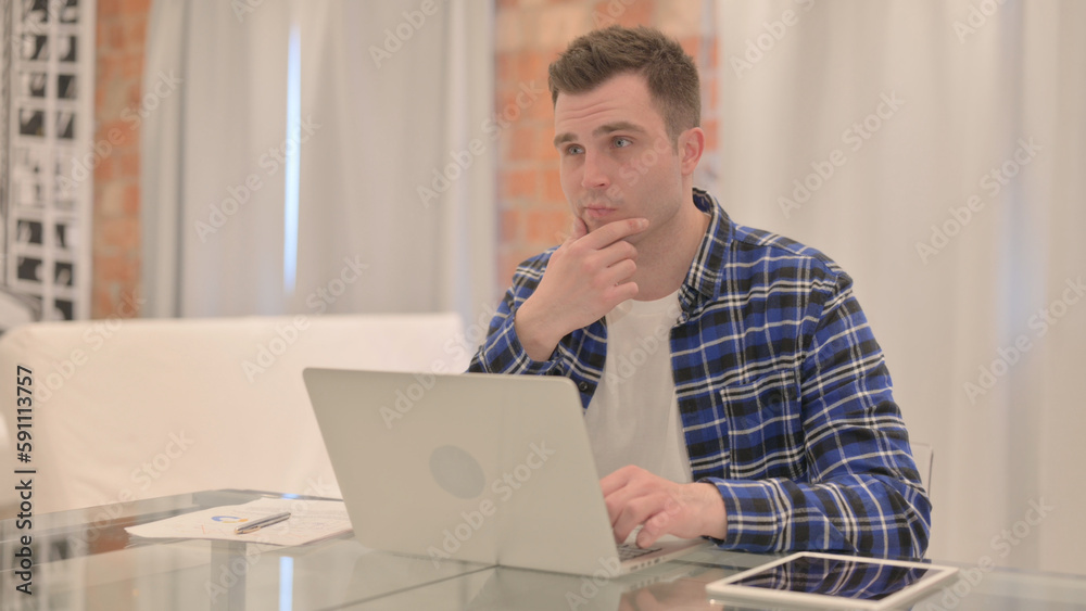 Young Casual Man Thinking and Working on Laptop Young Casual Man Thinking and Working on Laptop