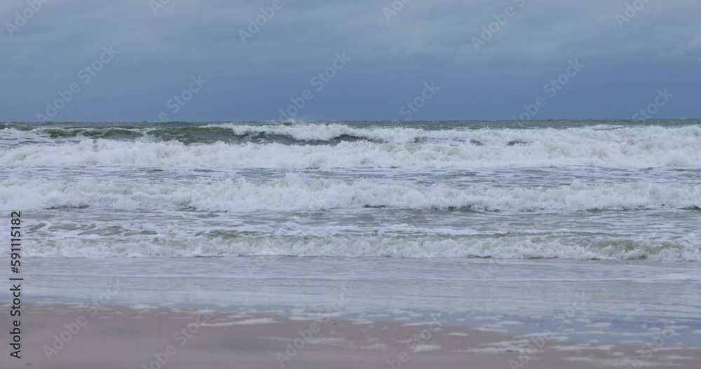 Static shot of stormy Baltic Sea in Poland with waves crashing on the beach, dark clouds, strong wind, and foam on the water surface Static shot of stormy Baltic Sea in Poland with waves crashing on the beach, dark clouds, strong wind, and foam on the water surface