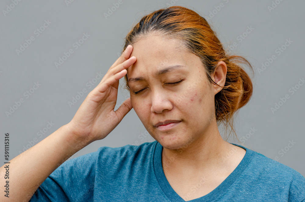 Asian women touch their temples right side, feel a headache or dizzy, feeling tired. need painkillers stand on grey background Asian women touch their temples right side, feel a headache or dizzy, feeling tired. need painkillers stand on grey background