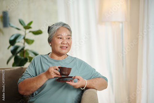 Portrait of senior woman enjoying cup of tea and looking away