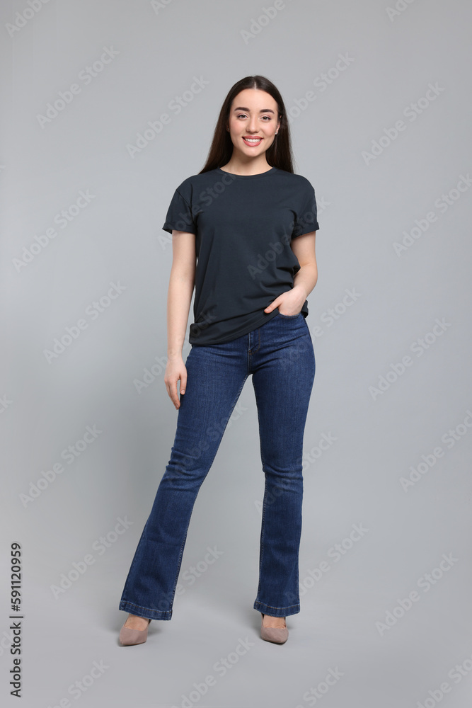 Young woman in stylish jeans on grey background Young woman in stylish jeans on grey background