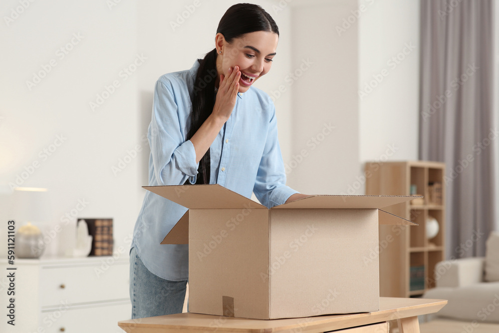 Happy young woman unpacking parcel at home. Internet shopping Happy young woman unpacking parcel at home. Internet shopping