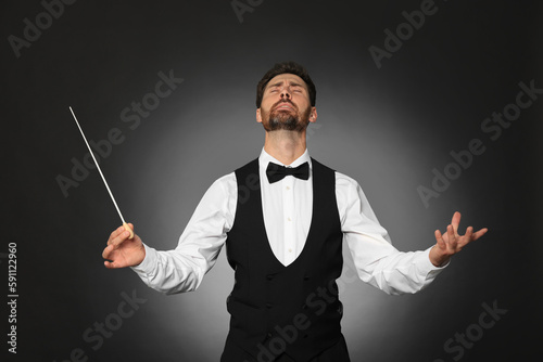 Professional conductor with baton on black background