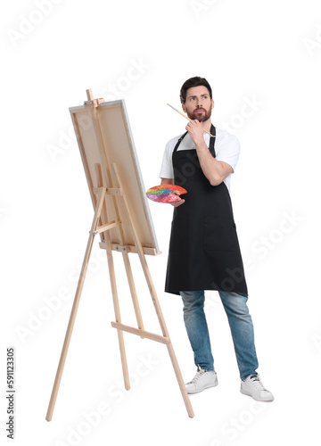 Artist with brush painting against white background. Using easel to hold canvas