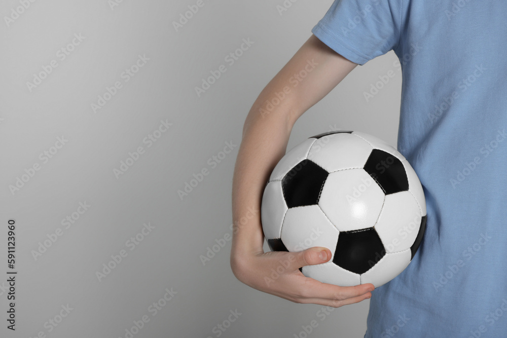 Boy with soccer ball on light grey background, closeup. Space for text