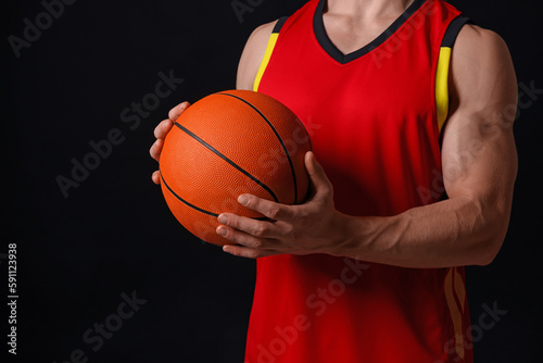 Athletic man with basketball ball on black background, closeup © New Africa