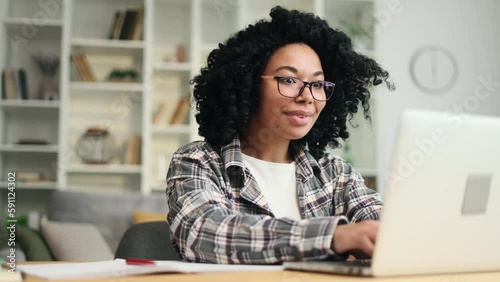 Portrait of young african american woman student looking at laptop computer screen with nod of approval and looking at camera with thumbs up at home Advise Approve Recommend Choice concept