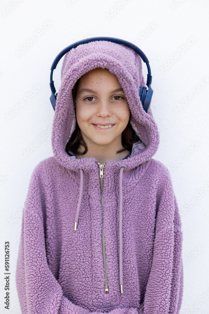 teenager in headphones and a purple hidi is standing on the street. Stylish boy. teenager in headphones and a purple hidi is standing on the street. Stylish boy.