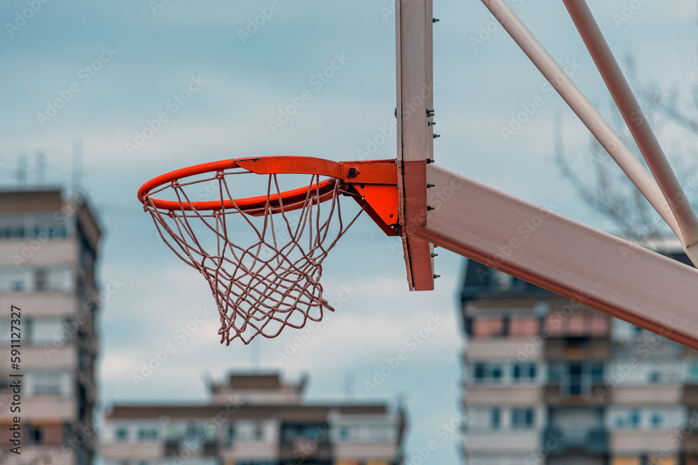 Street hoops, outdoor basketball court rim and the net with apartment building in background