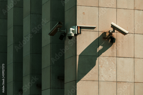 Old worn surveillance security cameras mounted on building wall photo