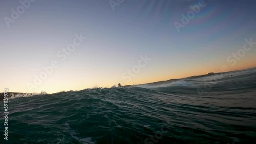 Surfer entering the Sea during Sunset at Costa da Caparica beach, Portugal