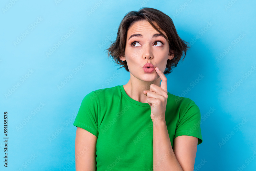 Photo of young tricky funny girl wear t-shirt point finger cheek look empty space pouted lips interested isolated on aquamarine color background Photo of young tricky funny girl wear t-shirt point finger cheek look empty space pouted lips interested isolated on aquamarine color background