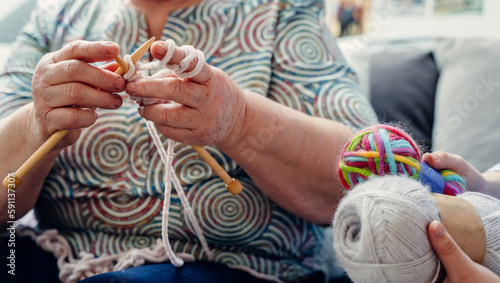 Close up of senior aged old woman holding knitting needles, enjoying creating warm clothing stuff with threads at weekend, leisure hobby activity pastime of elderly retired people.