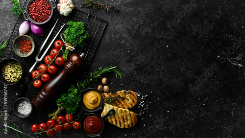 Black stone cooking background. Spices and vegetables. Top view. Free space for your text.