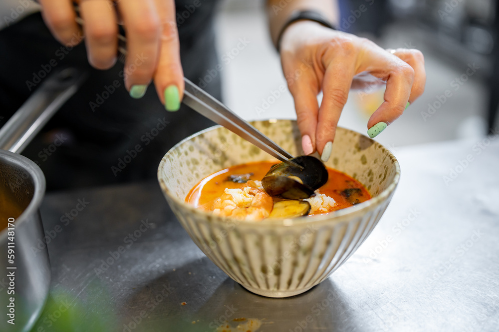 woman chef cooking seafood soup on restaurant kitchen