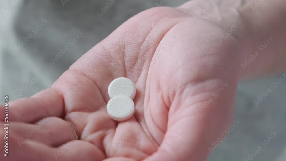 Woman taking painkiller white tablets or headache pills on female hand pouring tablets from meds bottle. Close up. Taking medicine, health care, pharmacy and treatment concept Woman taking painkiller white tablets or headache pills on female hand pouring tablets from meds bottle. Close up. Taking medicine, health care, pharmacy and treatment concept