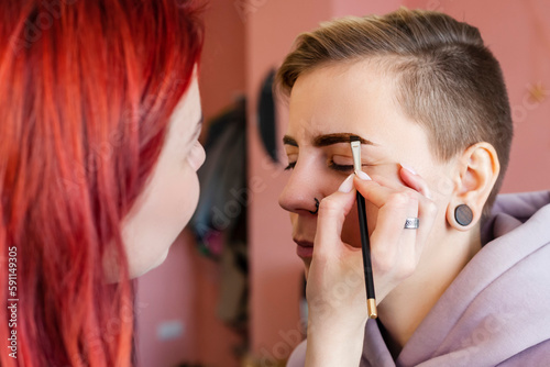 makeup artist or visagiste working on a woman's brows in a studio, paints the eyebrows. photo