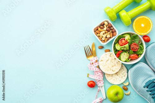Healthy lifestyle and losing weight background. Sport shoes, dumbell and healthy food on blue. Flat lay with copy space. photo