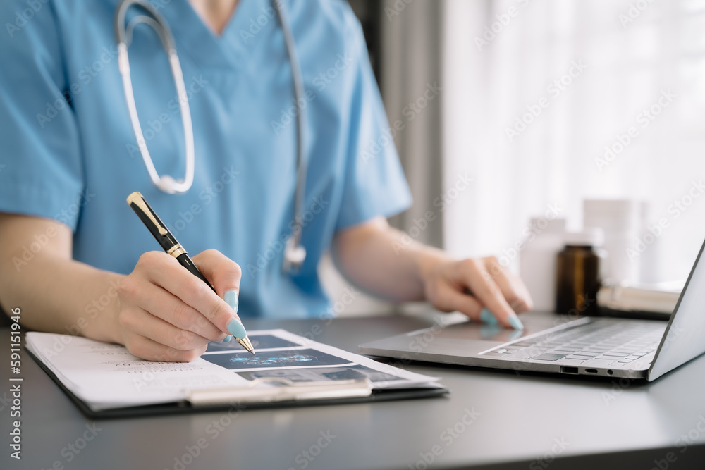 Doctor sitting at table and writing on a document report in hospital office. Medical healthcare staff and doctor service. Doctor sitting at table and writing on a document report in hospital office. Medical healthcare staff and doctor service.