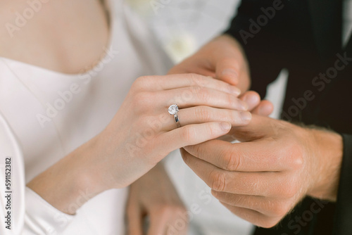 Gentle photo of the groom putting on the ring to the bride. Newlyweds