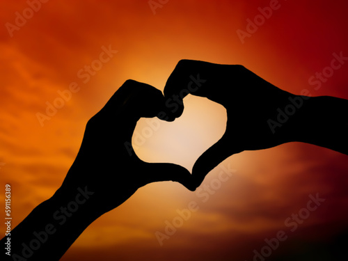 Love hand shape silhouette with beautiful sunset. Focus on hands