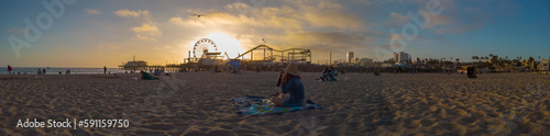 Los Angeles, California, USA, June 21, 2022: View of Santa Monica Beach and the Pier at sunset. Santa Monica Ferris Wheel and Roller-coaster.