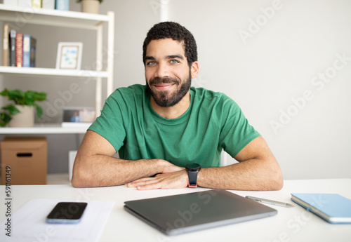 Smiling millennial arab guy manager with beard at workplace with smartphone with blank screen