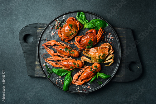 Red boiled crabs and crayfish with basil and garlic on a plate. Top view. Advertising restaurant photo.