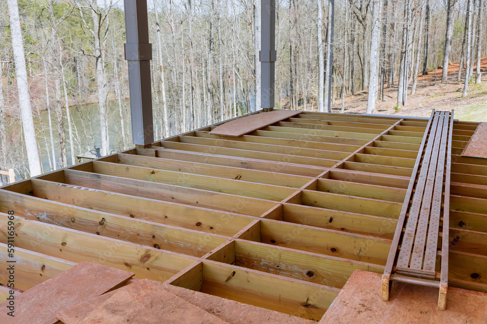 Obraz premium An newly constructed layout of flooring joists inside new custom built home with wooden deck patio