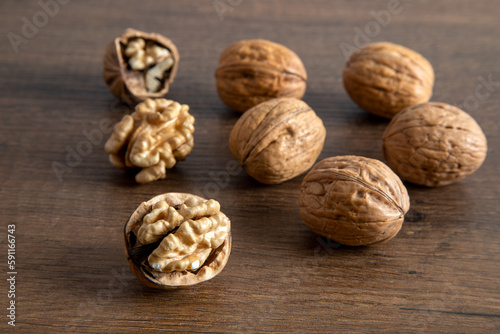 Peeled walnuts and whole walnuts in wooden table 