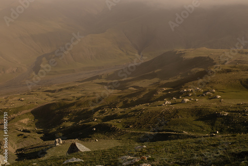 Sunny yellow and green mountain valley with velvety hilly slopes in golden sunlight with shadow, light mist on sunset in summer, detail. Mountain landscape, adventure in Dagestan. photo