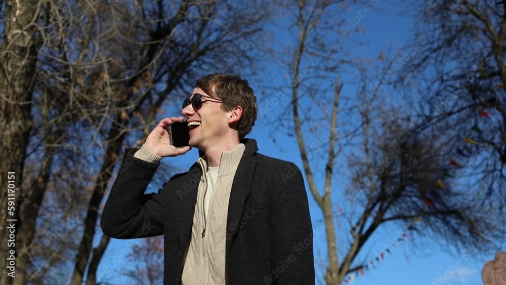 Young happy handsome man talking by smartphone outdoors in park Young happy handsome man talking by smartphone outdoors in park